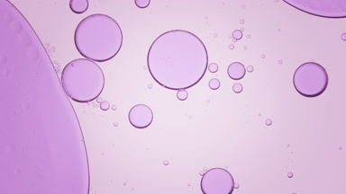 Violet bubble moves to the left in clear fluid with smaller ones