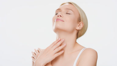 Blond woman in white crop top touches her chin, neck and sternum