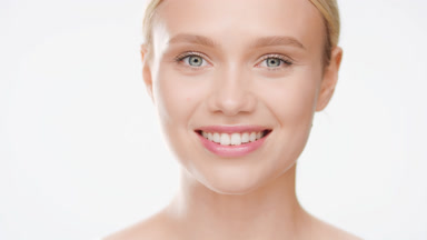 Blond woman opens eyes moving head up and smiling for the camera