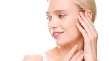 Girl in white top touches jaw line and turns head smiling wide