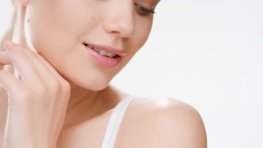 Cute young woman touches jaw line turning head and smiling wide