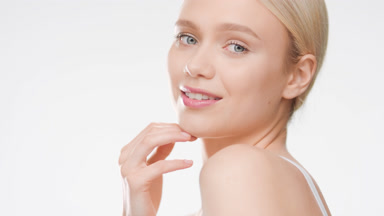 Pretty young woman touches chin turning body and smiling wide