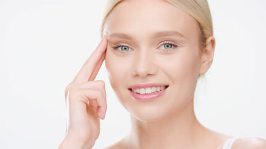 European blonde young woman lifts eye with fingers smiling wide