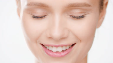 Slim Caucasian golden-haired woman smiles wide with closed eyes