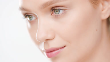Caucasian blonde female model opens her eyes smiling for camera