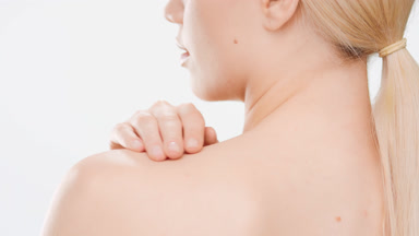 Young woman with long hair in ponytail touches neck and shoulder