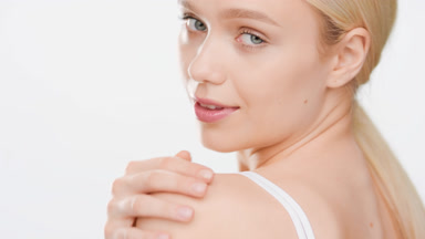 Woman turns to the camera smiling for it and touching shoulder