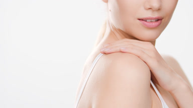 Young woman touches shoulder and jaw line turning to the camera