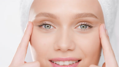 Fit woman with towel on head lifts eyes with fingers smiling