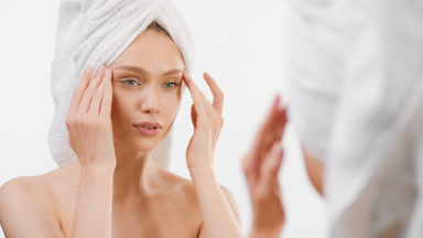 Fit woman lifts eyes with fingers smiling in front of the mirror