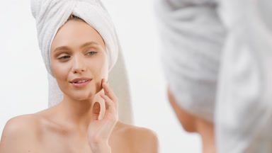 Beautiful fit woman touches face smiling in front of the mirror