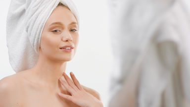 Caucasian slim woman touches body smiling in front of the mirror