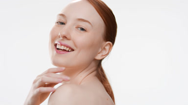 Slim European woman turns around and touches chin smiling wide