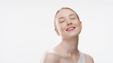 Beautiful slim red-haired young woman closes her eyes smiling