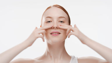 Caucasian girl with red hair touches her nose and cheeks smiling