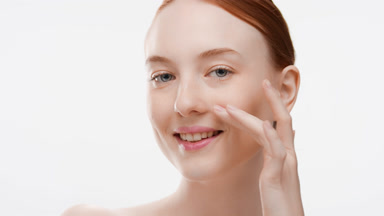 European fit young woman with ginger hair touches face smiling