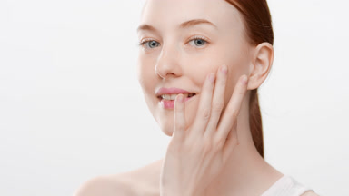 Beautiful Caucasian slim young woman touches cheek smiling wide