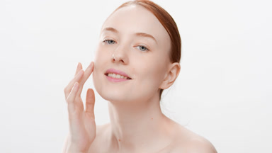 Cute fit Caucasian young red head woman touches face smiling