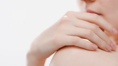 Female body care model touches her shoulder skin