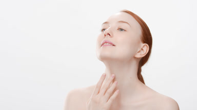 Pretty woman with orange hair touches chin and neck looking up