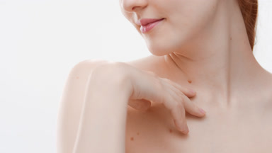 Woman with ginger hair touches clavicle and looks at the camera