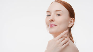 Woman touches clavicles and shoulder turning body and smiling