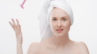 Funny young woman with a towel on hair throws away pink razor