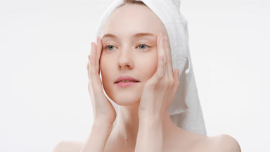 Attractive fit woman massages temples and touches cheeks smiling