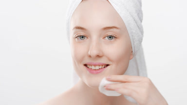 Cute fit young woman uses cotton pad for jawline smiling wide