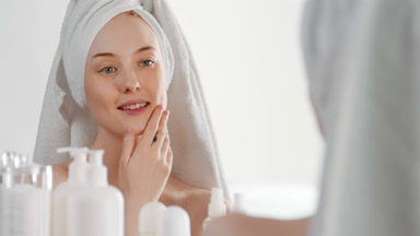 Beautiful woman touches jawline smiling wide in front of mirror