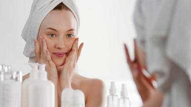 Pretty slim young woman touches face stretching skin and smiling