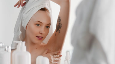 Fit European young woman touches armpit and hugs herself smiling