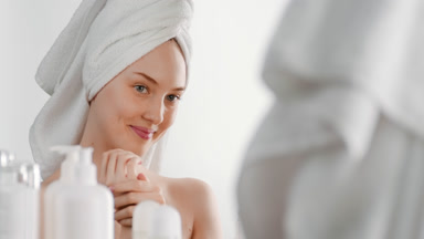 Cute fit young woman applies moisturizer on hands smiling wide