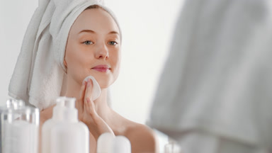 Beautiful fit young woman touches face with cotton pad smiling