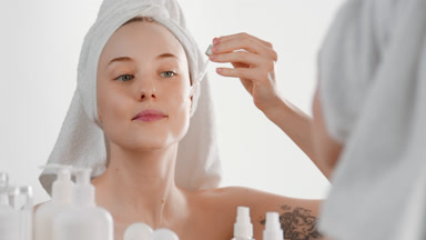 Gorgeous young woman puts essential oil on face using a dropper