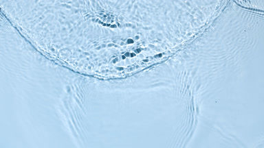 Water surface with waves and ripple on pale blue background