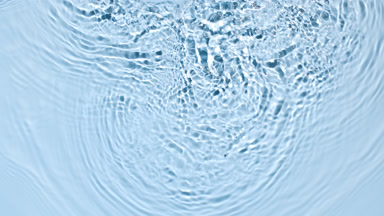 Pouring water splashing and making ripples on blue background