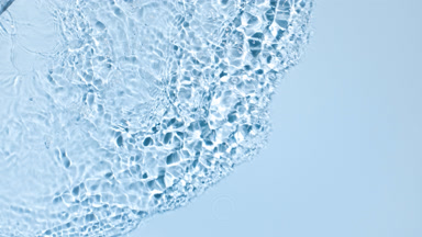 Poured water making splashes and ripples on blue background