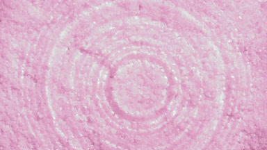 Drop making rings on water surface over pink mineral crystals