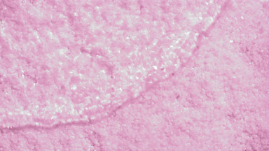 Wave making ripples on water surface over pink mineral crystals