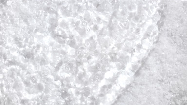 Water waves and ripples crossing over white mineral crystals