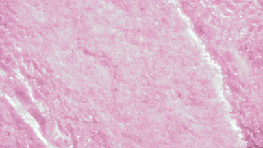 Water waves and ripples crossing over pink mineral crystals
