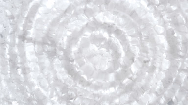 Water drop making ripples on water surface over white minerals