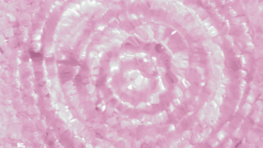Water drop making ripples on water surface over pink minerals