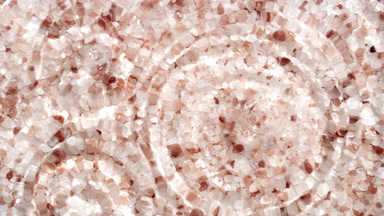 Multiple water drops falling on water surface over brown mineral