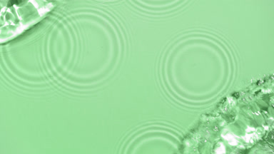 Poured water making splashes and ripples on green background