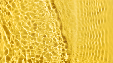Wave making ripples and splashes on water surface on yellow
