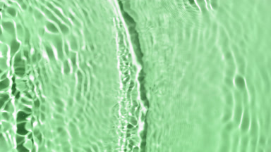 Water ripples creating waves and rings on green background