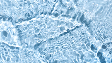 Poured water splashing and making and ripples on blue bg