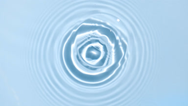 A drop making water ripples on water surface on blue background